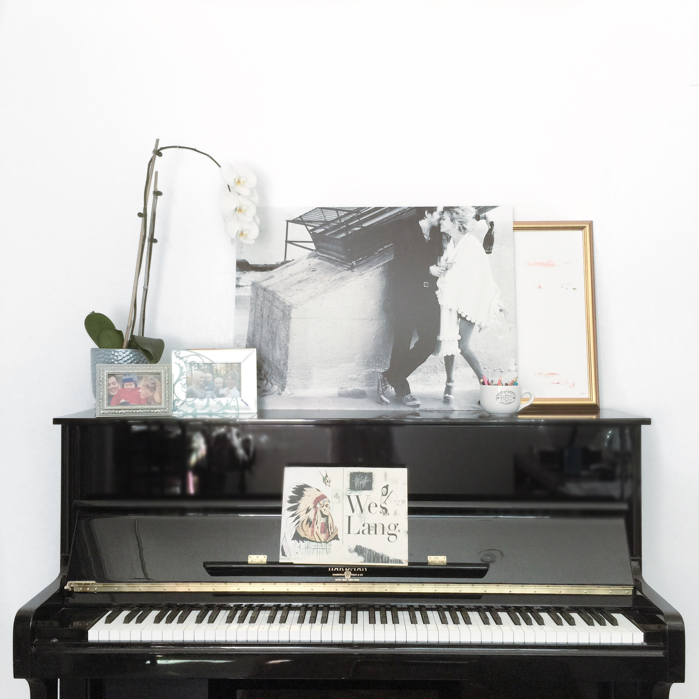 Black piano with orchid, photos and paintings on top